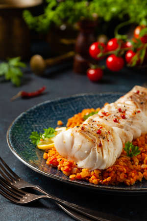 Fried pieces of cod loin, served on dark chickpeas. Dark painted background.の写真素材