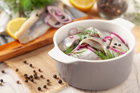 Herring fillets in oil. Served with onion in a bowl. Wooden background.の写真素材