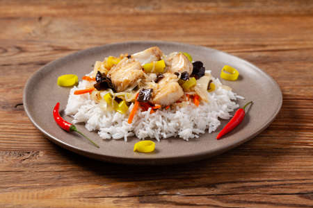 Chinese style cod, served on a plate with white rice. Natural wooden background.の写真素材