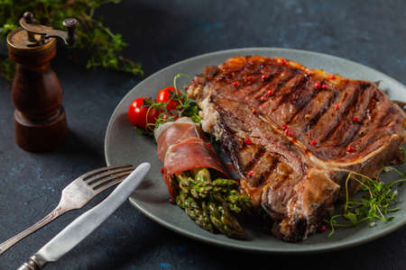 Grilled, medium-baked t-bone beef steak. Served with asparagus.の写真素材