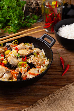 Chinese style cod, prepared in a wok. Natural wooden background.の写真素材