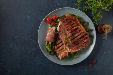 Grilled, medium-baked t-bone beef steak. Served with asparagus.の写真素材