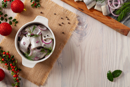 Herring fillets in oil. Served with onion in a bowl. Wooden background. Christmas decorationの写真素材