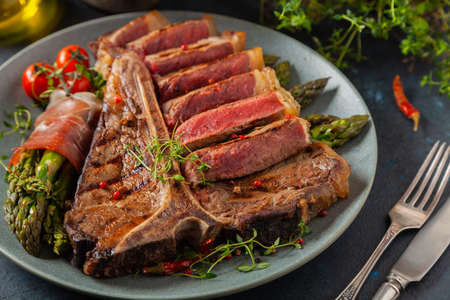 Grilled, medium-baked t-bone beef steak. Served with asparagus.の写真素材