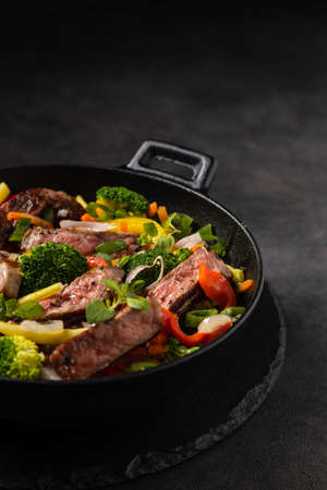 Beef with vegetables. Prepared in a wok. Dark background.の写真素材