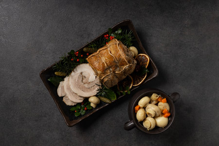 Whole cooked bacon roulade. Tied with a string. Served with cranberries, mushrooms or pickled cucumbers. Dark background.の写真素材