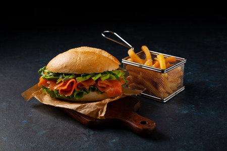 Salmon sandwich. A large roll. Dark mood. Black background.の写真素材