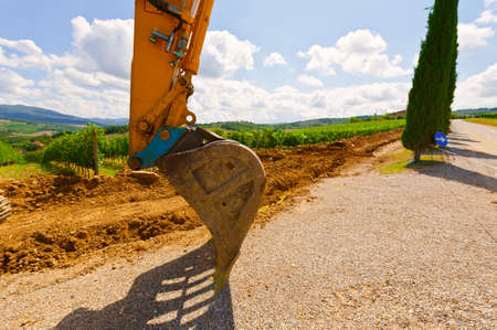 Excavator Bucket on the Asphalt Road near the Vineyard