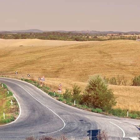 Winding Paved Road between Autumn Plowed Fields in the Tuscany, Vintage Style Toned Pictureの写真素材