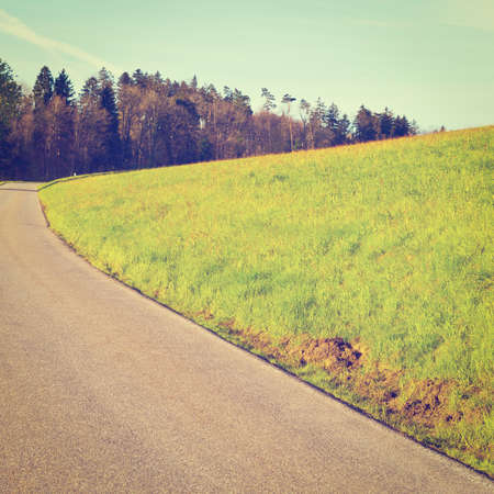 asphalt road leading to the farmhouse in the swiss alpsの写真素材