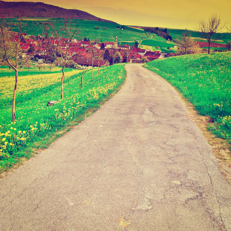 asphalt road leading to the small city in the swiss alps at sunsetの写真素材