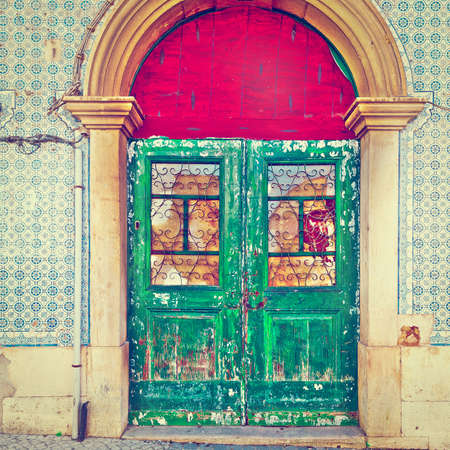 Shabby Wooden Door in the Wall Decorated with Portuguese Ceramic Tilesの写真素材