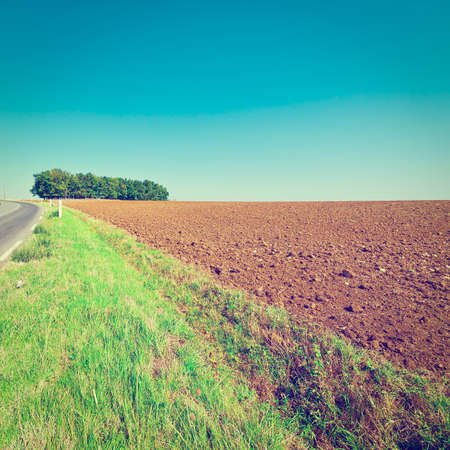 Winding Asphalt Road between Autumn Plowed Fields in Franceの写真素材
