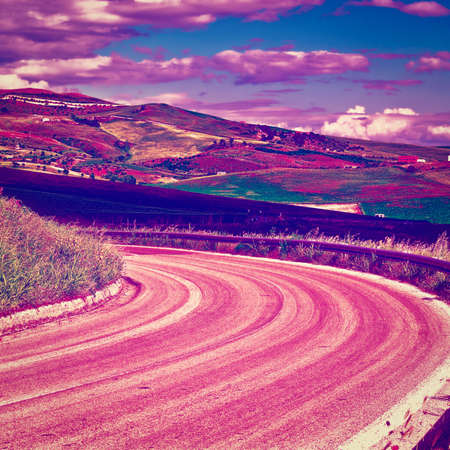 Winding Asphalt Road between Stubble Fields of Sicily at Sunset  の写真素材