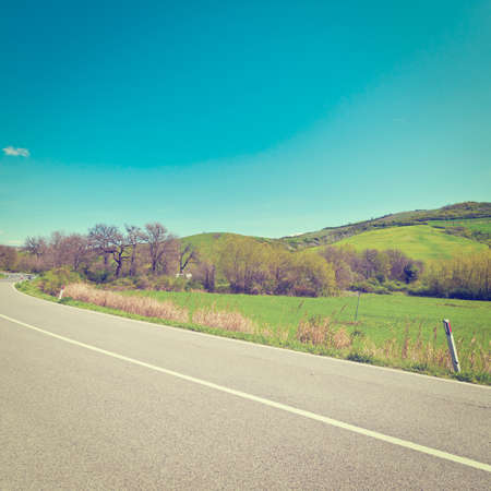 Winding Asphalt Road between Spring Fields in Tuscanyの写真素材