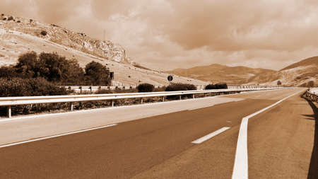 Winding Asphalt Road between Fields with Many Hay Bales on Sicily, Vintage Style Sepia