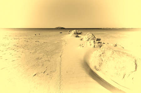 View of a small island from the Israeli shore of the Mediterranean Sea. Sand blowing over beach dune in wind in Israel. Vintage Style Toned Pictureの写真素材