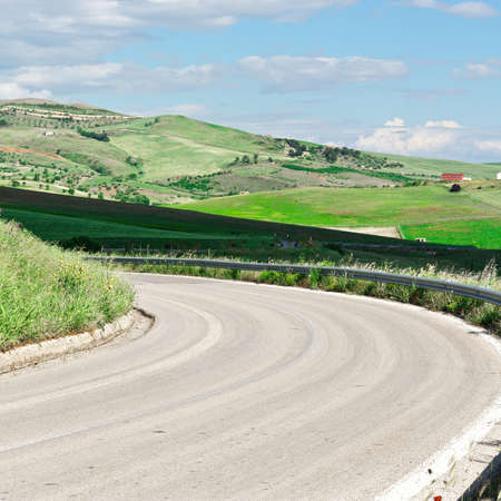 Winding Asphalt Road between Stubble Fields of Sicilyの写真素材