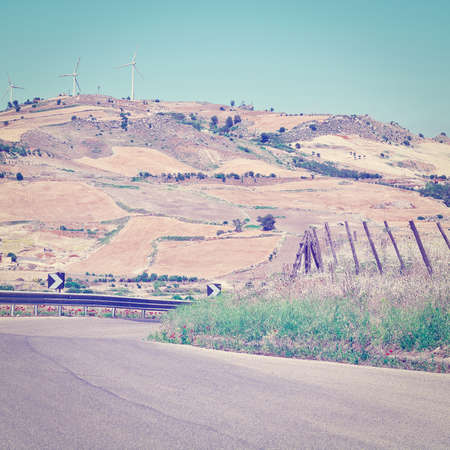 Winding Asphalt Road on the Background of the Modern Wind Turbines in Sicilyの写真素材