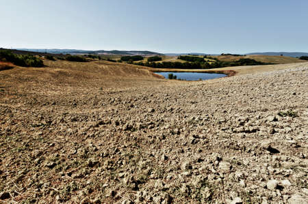 Pond for irrigation between stubble fields in Italy. Plowed hills of Tuscany in the autumn. Plowed...