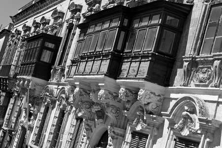 Typical narrow street on the island of Malta. Buildings with traditional colorful maltese balconies in historical part of Valletta. Black and white pictureの写真素材