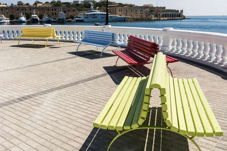 Colorful park benches on the embankment of Valletta. Promenade on the background of the bay in Maltaの写真素材