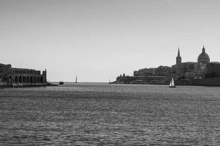 Cityscape view with Basilica of Our Lady of Mount Carmel on the island of Malta. Buildings with traditional colorful maltese balconies in historical part of Valletta. Yachts in the harbor on the background of city. Black and white pictureの写真素材