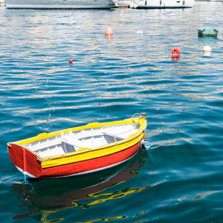Colored buoys floating in port of Malta for mooring of yachts. A wooden cheap boat among the luxury shipsの写真素材