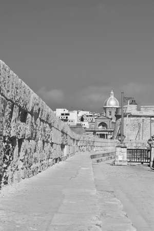 Narrow street along the wall of fortress on the island of Malta in historical part of Valletta. Black and white pictureの写真素材