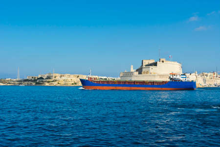 Cargo ship leaves the harbor of Valletta.の写真素材