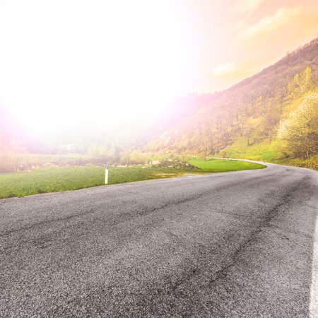 Morning mist over the asphalt road in the Italian Alps in Piedmont. View of the mountain valley with highway at sunriseの写真素材