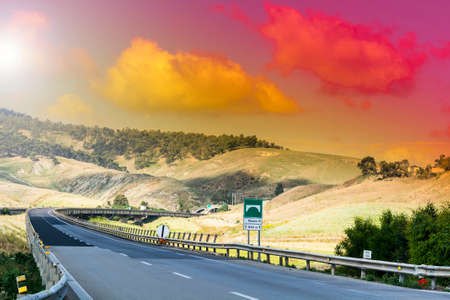 Landscape of Sicilian hills at sunrise. Asphalt road elevated by columns due of frequent earthquakes...