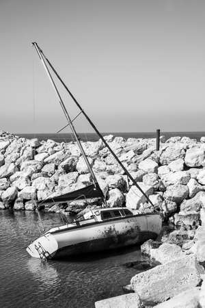Breakwater protecting the beach of Mediterranean sea in Israel. Yacht floating on the side after the...