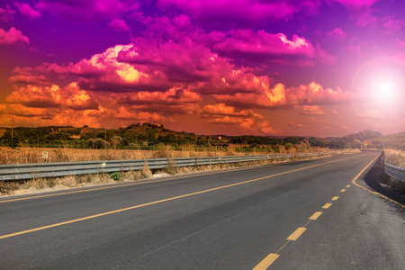 Straight asphalt road near vineyard in Italy early in the morning. Italian landscape at sunrise, hills, fields, pasture and sunlightの写真素材