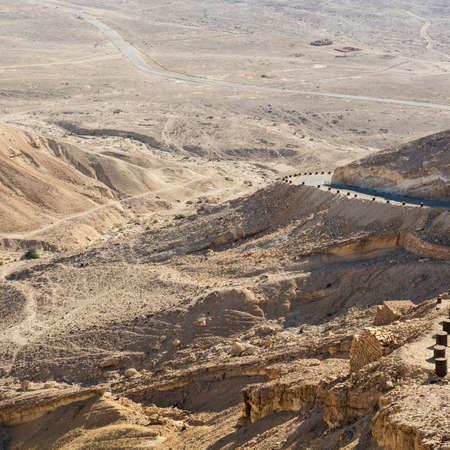 Asphalt road in the Negev Desert in Israel. Breathtaking landscape of the rock formations in the Southern Israel. Dusty mountains interrupted by wadis  and deep craters.の写真素材