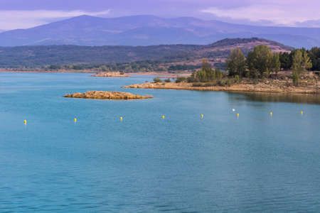 Mountain lake in Spain early in the morning. Spanish landscape at sunrise, hills, water, beach and sunlightの写真素材
