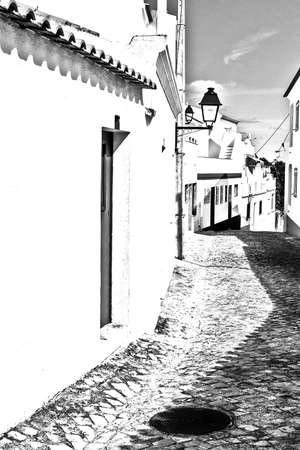 View on the narrow street with ancient buildings in medieval Portuguese city. Black and white photoの写真素材