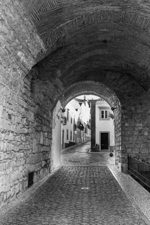 View through the arch on the narrow street with ancient buildings in medieval Portuguese cityの写真素材