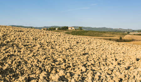 Italian wine farm surrounded with plowed sloping hills of Tuscany in the autumn. Rural landscape with vineyard and fields after harvest.の写真素材