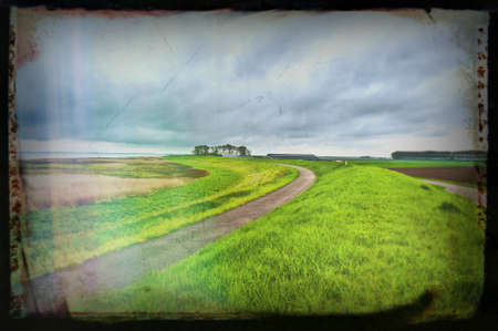 Agriculture on Land Reclaimed from the See in Netherlands. Asphalt road along protective dam and canal in Hollandの写真素材