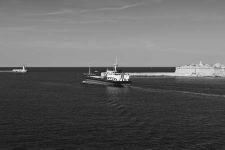 Cargo ship leaves the harbor of Valletta. Lighthouses indicate the entrance to the ports of Malta....