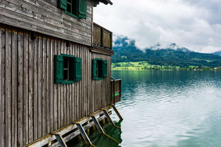 Rain and clouds on the Wolfgangsee in Austria. Morning mist over the Austrian landscape with lake, boat hangars, forests,  pastures, meadows and villagesの写真素材