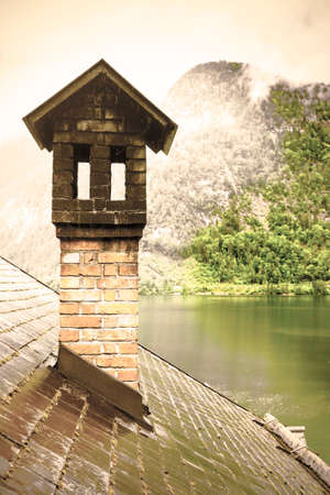 Rain and clouds on the Hallstattersee in Austria. Morning mist over the Austrian landscape with lake, forests, fields, pastures, meadows and wet roofs. Retro styleの写真素材