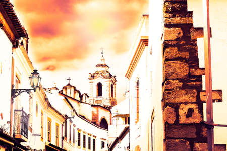 View on the narrow street with ancient buildings in medieval Portuguese city at sunset
