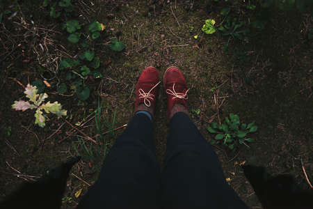 Women's legs in red boots standing in autumn forestの写真素材