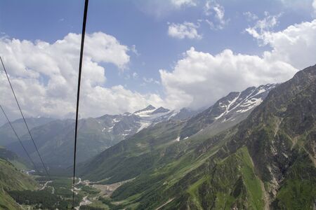 Sky in the clouds green and snow on the mountains, North Caucasus Elbrus regionの写真素材