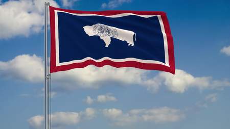 Flag of Wyoming - US state fluttering in the wind against a cloudy sky 3d renderingの写真素材
