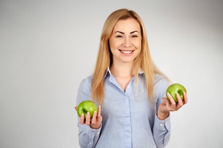 Happy young woman eating apples on kitchenの写真素材