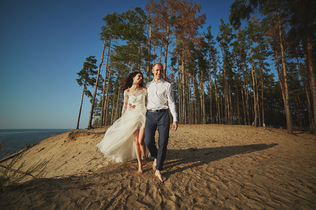 Just married couple running on a sandy beachの写真素材