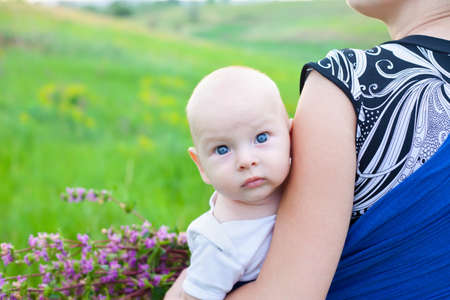 baby boy on hands of mother on green meadow 
